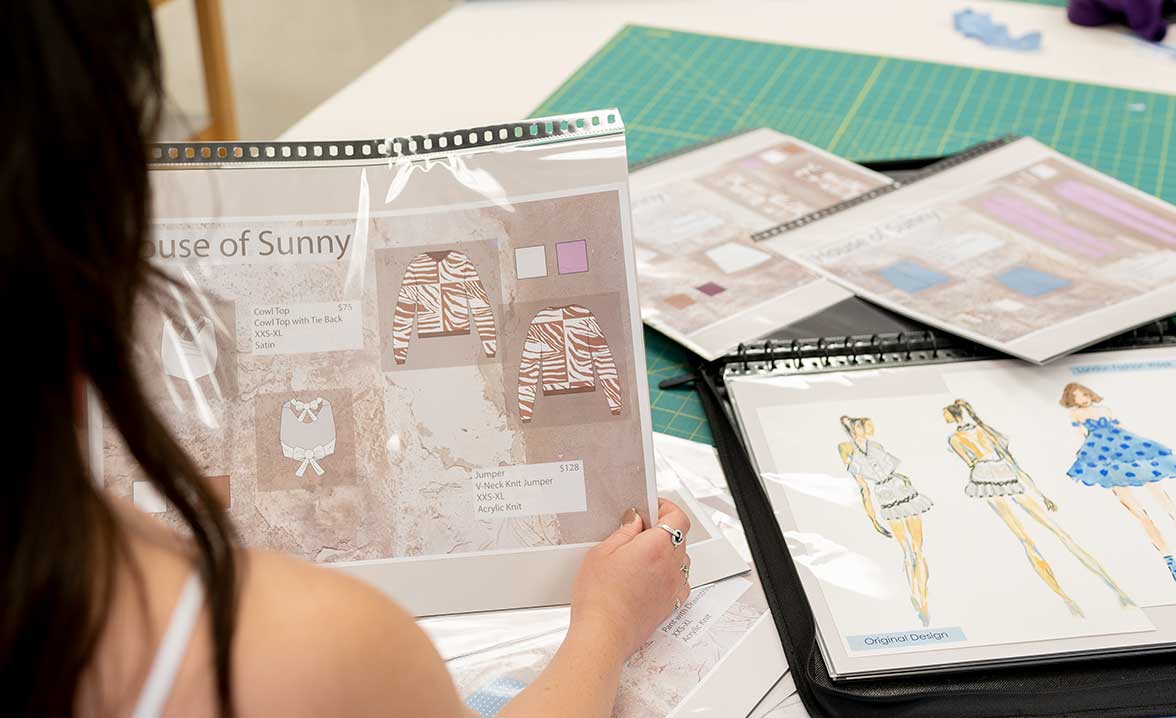 Textile and apparel student examines moodboard and sketches