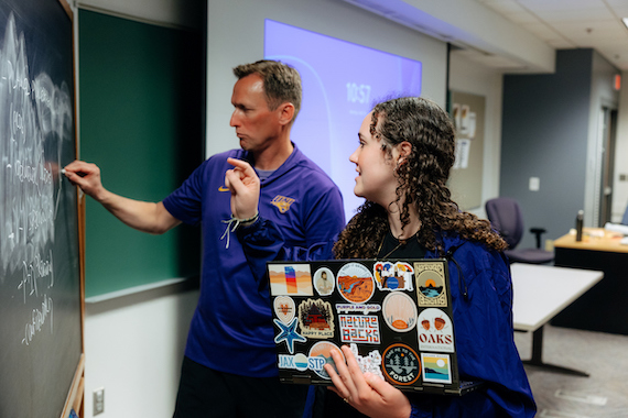 UNI professor working with a student at a chalk board