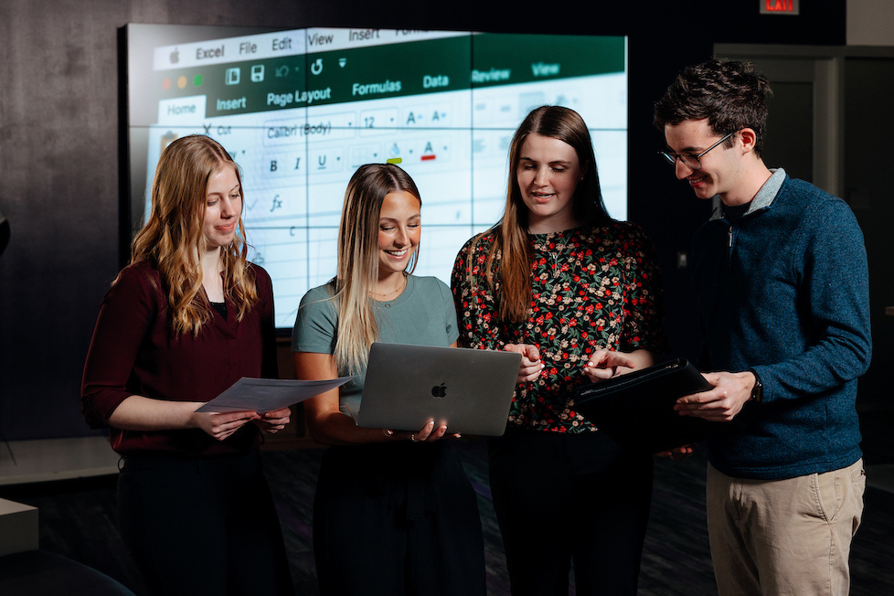 Business students in a group looking at a laptop