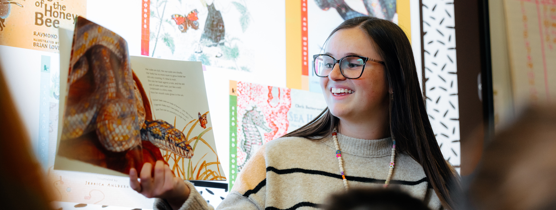 Student teacher reading a book in a classroom