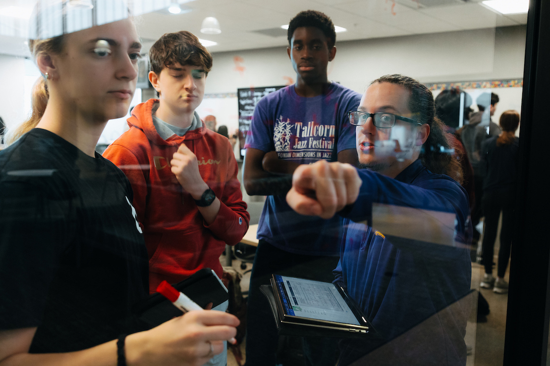 Student teacher at a glass board with high school students