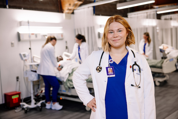 Nursing student in her purple scrubs and white coat